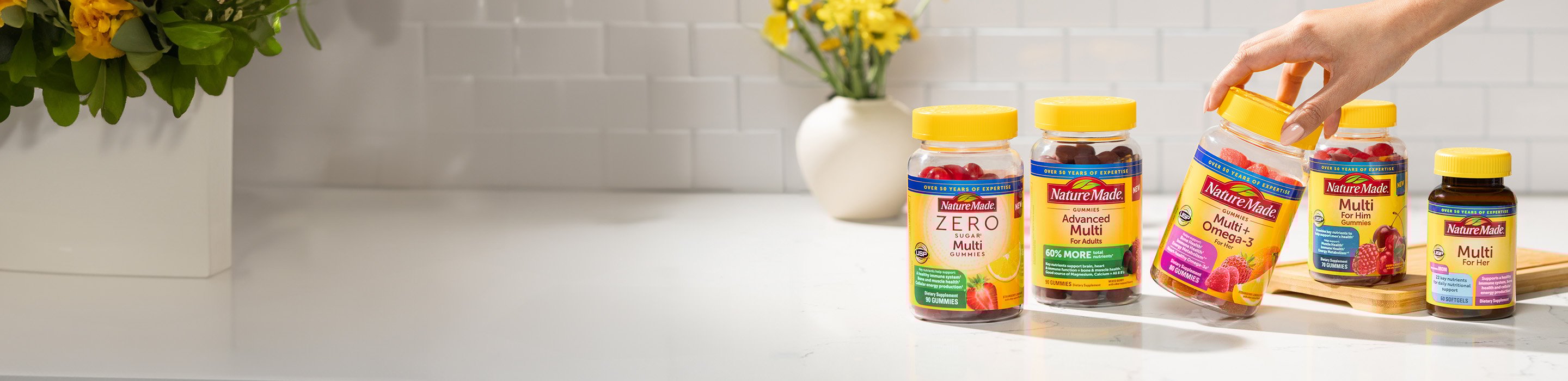 A variety of Nature Made multivitamin supplements, including gummy vitamins and tablets, displayed on a kitchen counter.