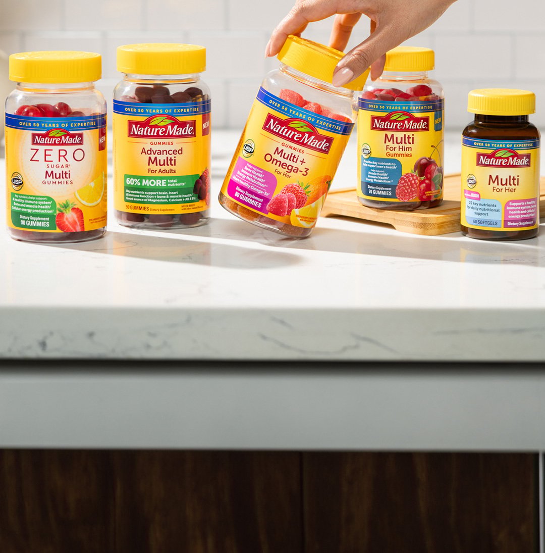 A variety of Nature Made multivitamin supplements, including gummy vitamins and tablets, displayed on a kitchen counter.